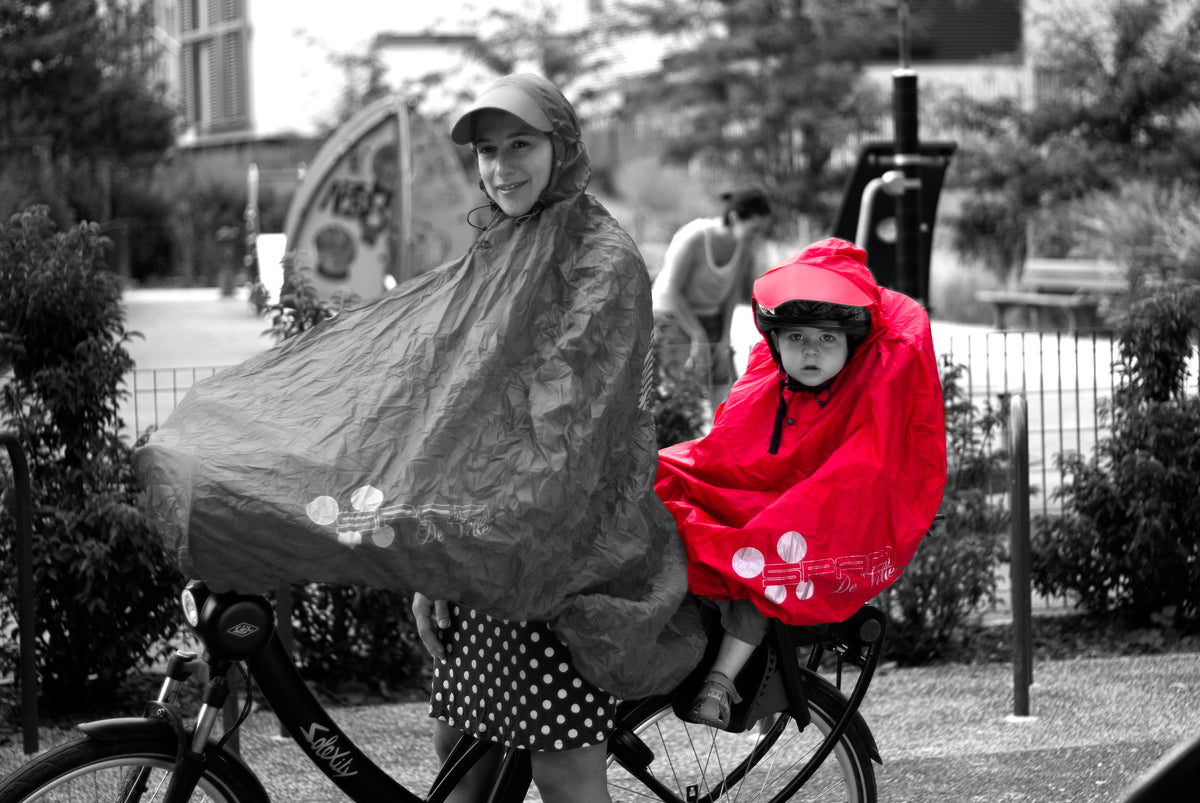 Maman avec sa cape de pluie FULAP et son fils sur le siège arrière avec son poncho vélo FULAP Junior rouge sur un vélo Solex vue de profil SPAD De Ville
