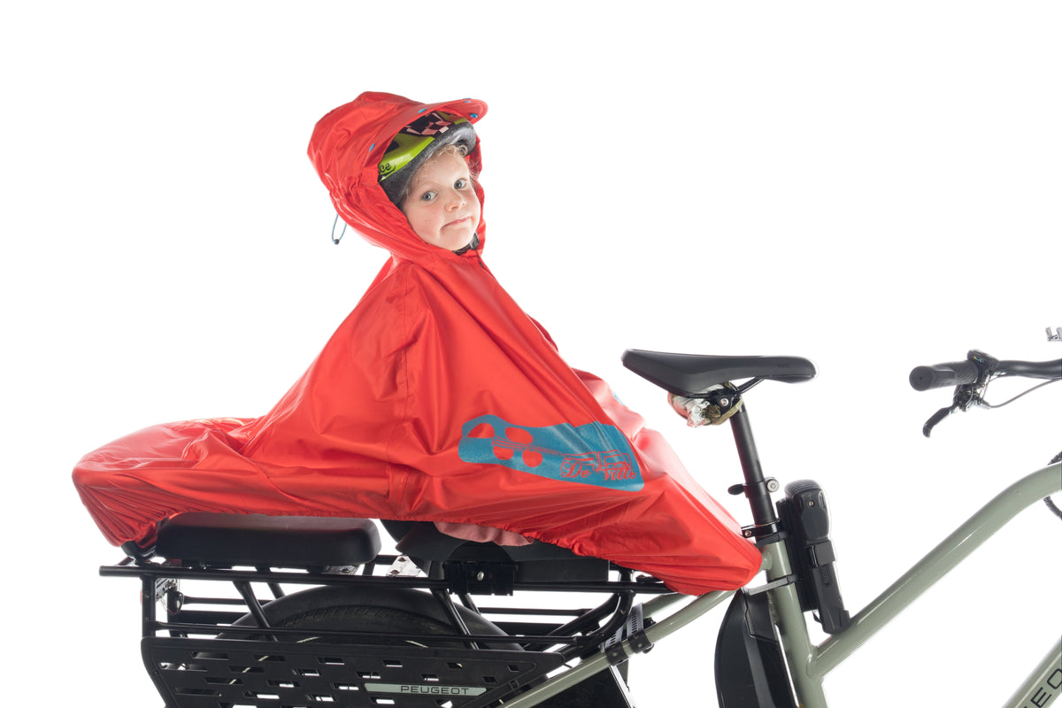 SPAD De Ville FULAP Junior la cape de pluie vélo multiusages pour les enfants de 1 à 12 ans rouge haute visibilité motifs rétro-réfléchissants bleu vue de profil sur longtail peugeot douze cycle avec un monkey bar